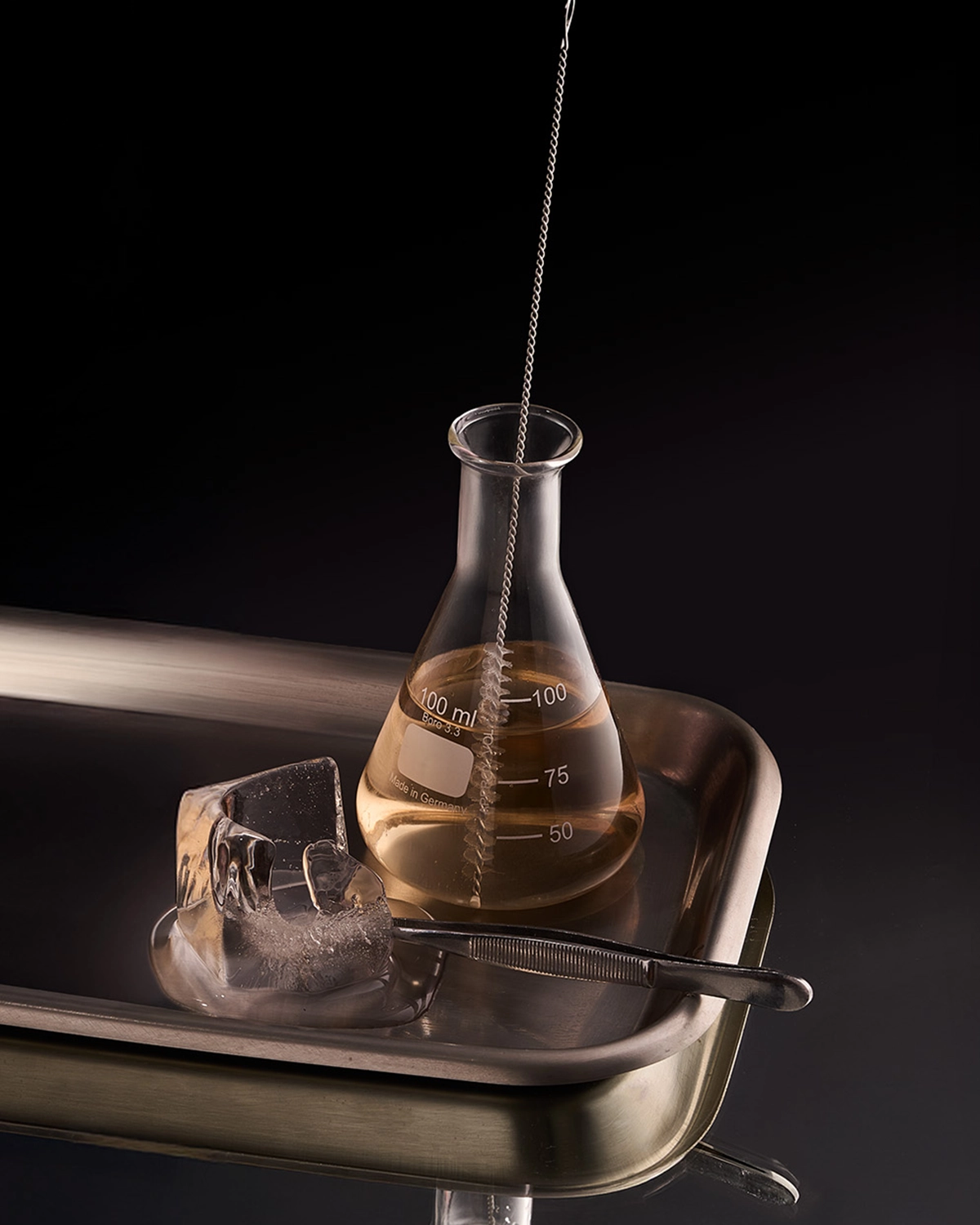 Coctelería de autor en matraz de laboratorio sobre bandeja de acero