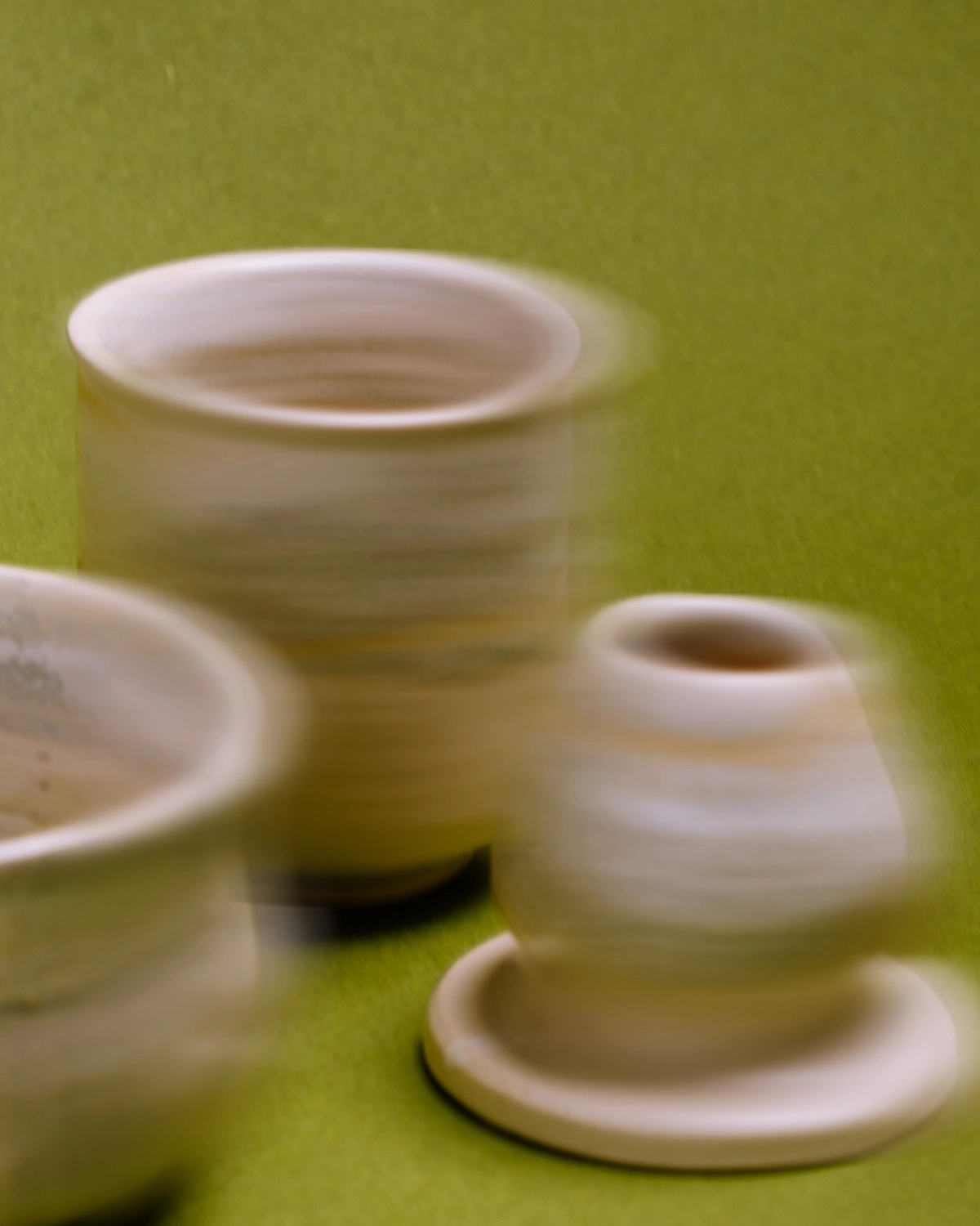 Piezas de cerámica artesanal en movimiento sobre fondo verde