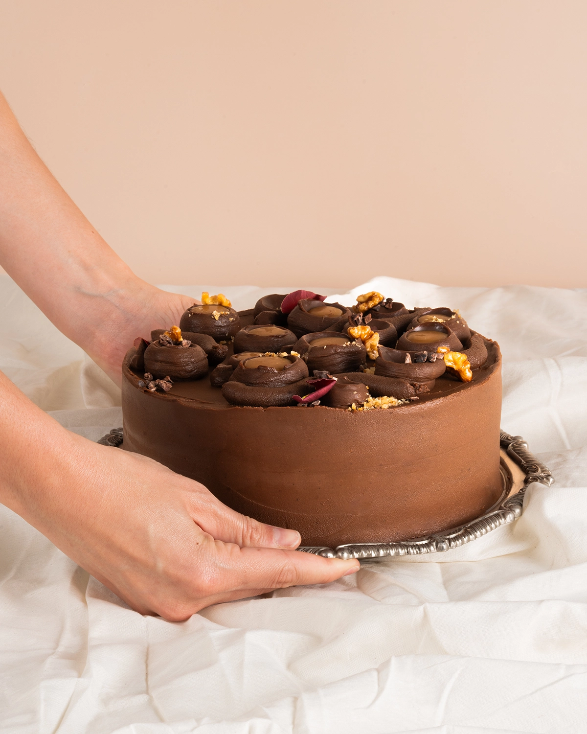 Torta de chocolate y nueces sostenida sobre una bandeja de plata