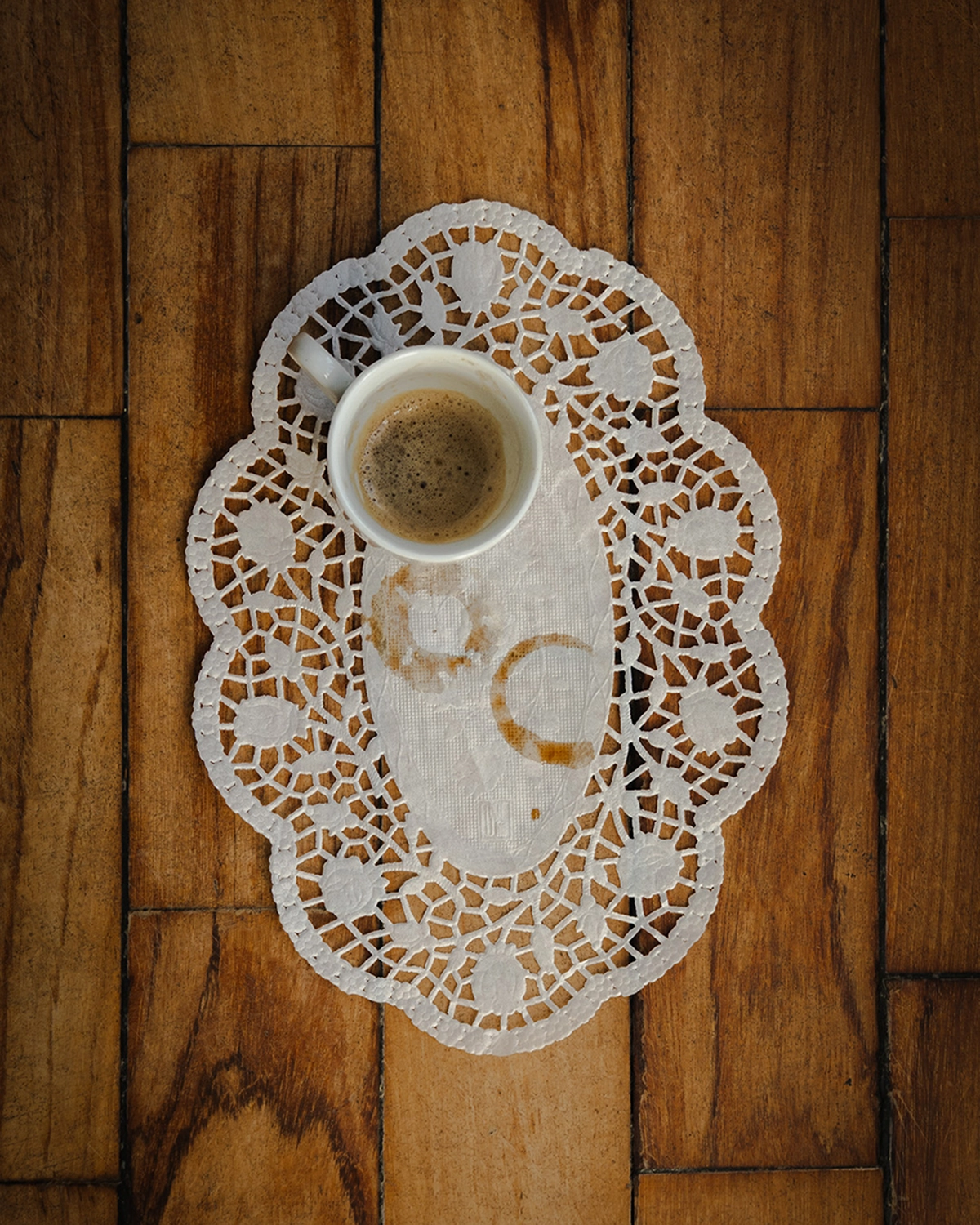 Taza de espresso sobre blonda de papel, fotografía cenital de producto